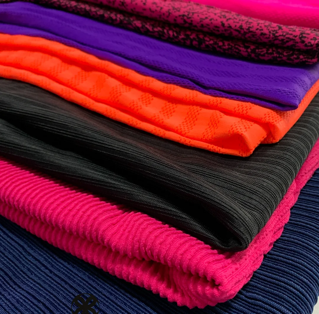 Close de malhas caneladas dobradas em azul-marinho, pink, preto e laranja